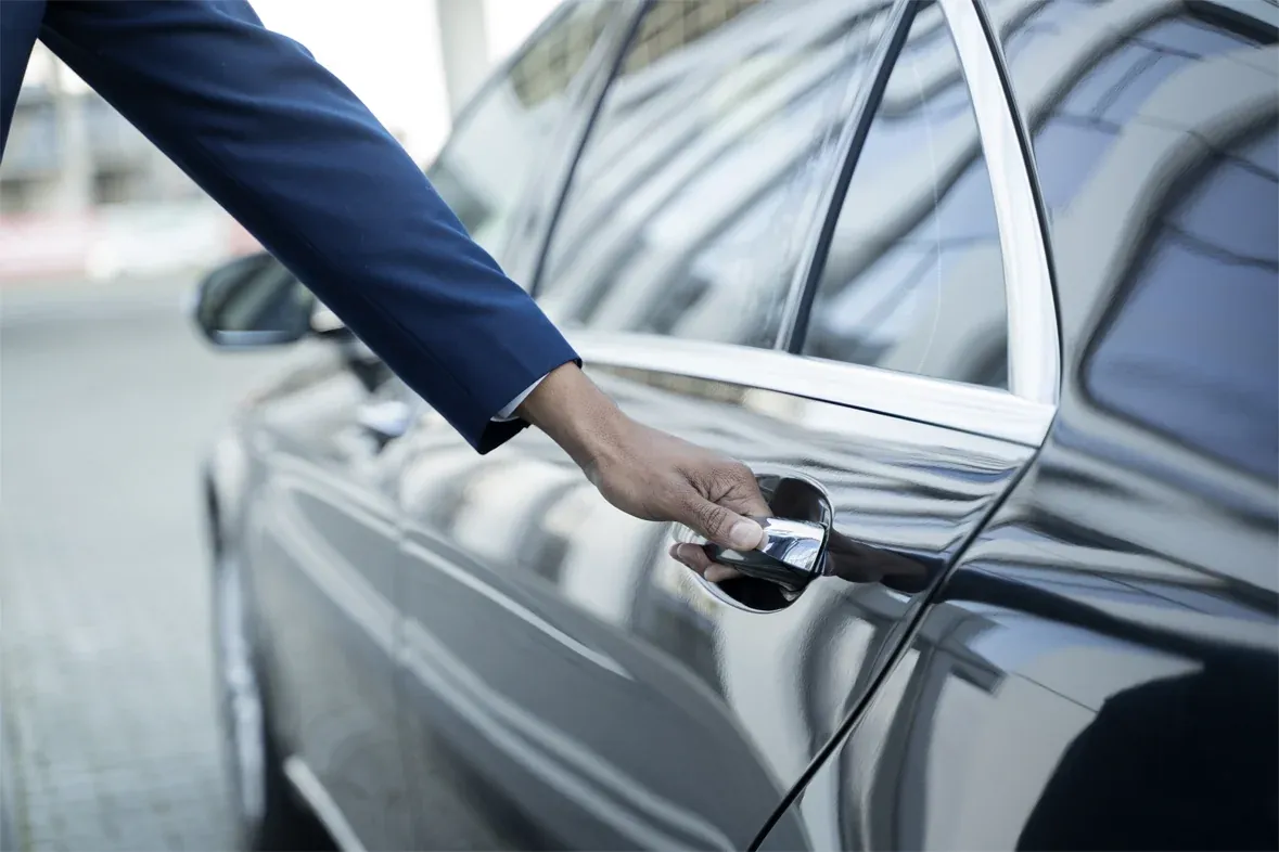 Chauffeur privé ouvrant la portière d'une voiture de luxe